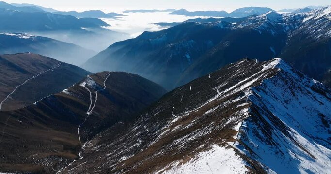 endless landscape of mountains, with snow covering the peaks and clouds in the valley