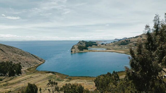 Drone footage captures the enchanting beauty of Titicaca Lake with a quaint hamlet and agricultural terraces, showcasing the harmonious blend of nature and culture.