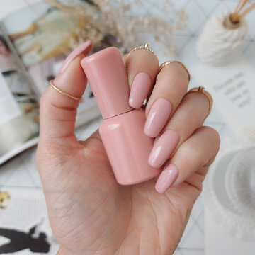 A beautiful woman's hands with a beige wedding manicure. The nail design is in the form of a soft square, the color is natural pink. Long nails made of polygel for extension with tips and gel polish.