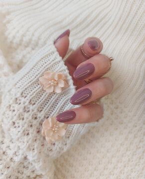 A beautiful woman's hands with a taup manicure. The nail design is in the form of a soft oval almond, the color is natural pink. Long nails made of polygel for extension with tips and gel polish