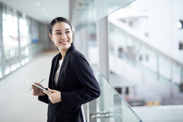 Asian business woman holding a tablet looking away, Fashion business photo of beautiful girl in casual suite with tablet .
