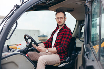 Naklejka premium Young Rural Tractor or Combine driver sitting in the cab. Farming and harvesting