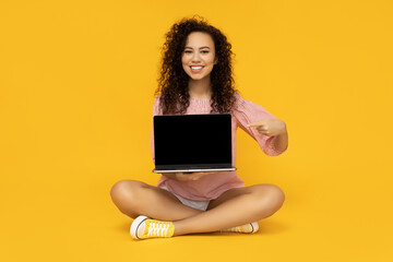 Naklejka premium Young woman with laptop on yellow background