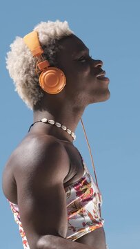 Transgender person dancing while listening to music with headphones outdoors.