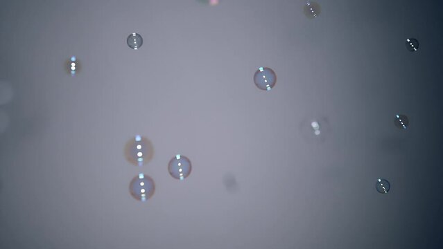 Bubbles blow down from top left corner float daintily in air, grey background
