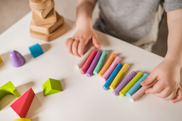 A three-year-old boy plays with crayons, plasticine and a construction set. The concept of early development and sensory perception. Finger games in kindergarten