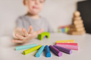 Happy boy play with plastiline and constructor. Kids hands with colorful clay. Close up.  Early childhood development and behavior modification. Finger sensory therapy and speech therapist