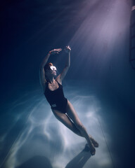 A girl in a mask underwater in the pool in the water