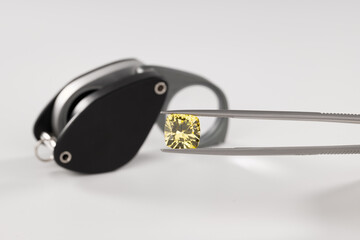 Yellow diamond and magnification glass on background