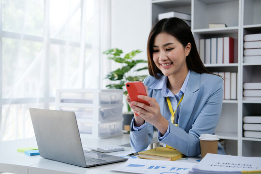 Young asian woman using smartphone chatting video conference online sitting in living room at home. Business Woman shopping online by smartphone.