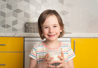 Portrait of a girl with a glass of delicious fresh milk in the kitchen. The concept of world milk...