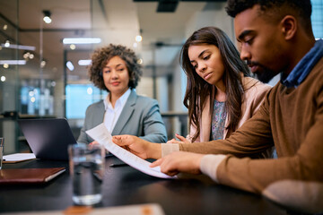 Young black couple analyzing paperwork on meeting with insurance agent.