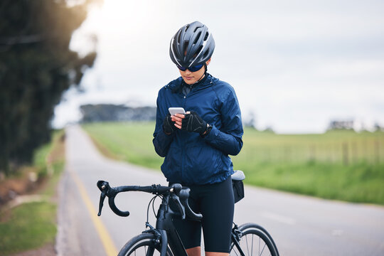 Woman, bicycle athlete and outdoor with phone for social media technology, mobile app or search gps direction. Female cyclist, bike and typing on smartphone for network notification, sport or cycling - Powered by Adobe