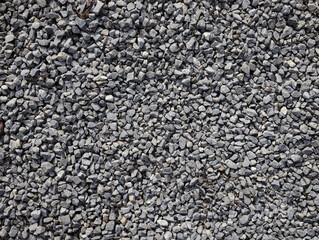 Gray stone gravel texture background. Broken stone or crushed rock texture with place for text. dark background of crushed granite gravel, close up top view.