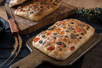 Focaccia with olive tomatoes and rosemary. Homemade Italian Sourdough Bread on white cafe table. - 594565218
