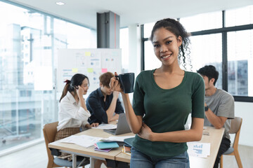 Portrait of a happy woman standing in a corporate office during a team analysis meeting. Young businesswoman discussing and analyzing a creative project in the company conference room