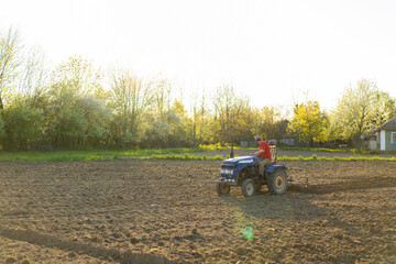 The tractor drives across the field and cultivates the land. Agricultural vehicle works in...