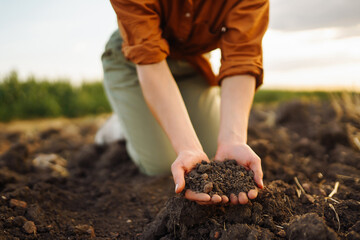 Woman farmer's hand checks soil before growing vegetable seeds or plant seedlings. Hand of an experienced farmer with a clipboard collects the soil. Concepts of ecology and gardening.