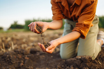 Woman farmer's hand checks soil before growing vegetable seeds or plant seedlings. Hand of an experienced farmer with a clipboard collects the soil. Concepts of ecology and gardening.