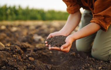 Woman farmer's hand checks soil before growing vegetable seeds or plant seedlings. Hand of an experienced farmer with a clipboard collects the soil. Concepts of ecology and gardening.