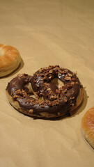 Freshly Baked Homemade Soft Pretzel covered in chocolate and crushed nuts on bake paper. Top side View with Copy Space