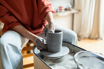 Fototapeta na wymiar Hands of craftswoman ceramist working sitting in cozy workshop using potter wheel for make clay tableware. Process of creating handmade chinaware in art studio for creative entrepreneurs and artisans 