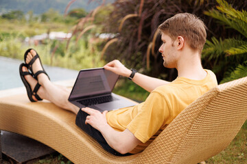 Young digital nomad working remotely on his laptop in Bali. Freelancer Man in workation video call....