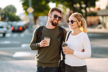 Happy young couple spending time together, drinking coffee, having fun walking around the morning city. Youth, love, time together, lifestyle.