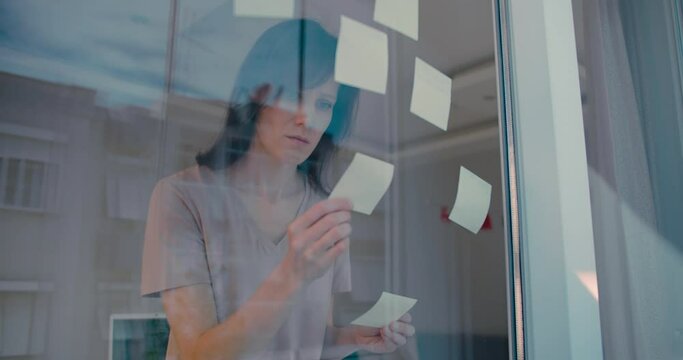 Businesswoman standing in front transparent glass write the sticker idea brainstorm meeting for business plan at workplace