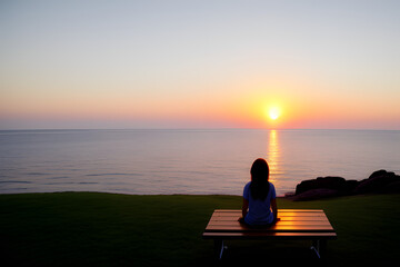 Woman sitting on a bench watching the sunset