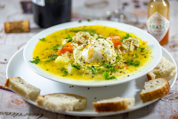 A bowl of chicken soup with bread on the side, know as 
