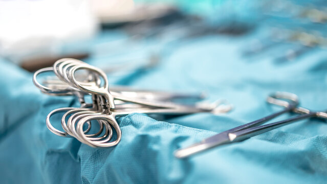 Surgical clamps and medical equipment on surgical tray.Surgical scissors on medical table intend to blur background inside operating room.Medical tools inside operating theater with green table.
