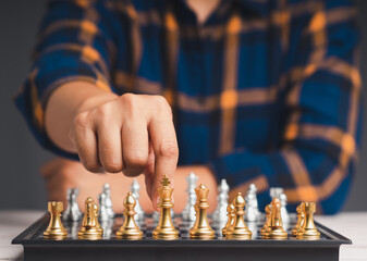 A man playing a game of chess on a chessboard while sitting at the table