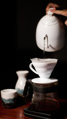 Barista slowly pouring hot water into filtered coffee beans, japanese style manual brew, iced beverage single origin
