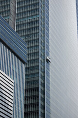 Obraz premium 超高層ビルの外壁を掃除する作業員の風景