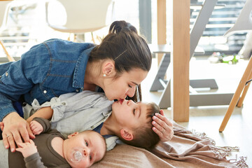 Glückliche Mutter kuschelt mit zwei Kindern