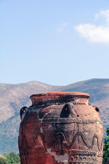Huge pottery vase in the archaeological site of the Palace of Malia with mountains in the background on a sunny day, Crete, Greece