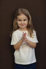 cute blond little girl in white t-shirt and jeans closeup photo on dark brown background