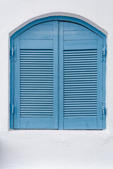 Closed blue wooden shutters on a white painted house facade in mediterranean architectural style