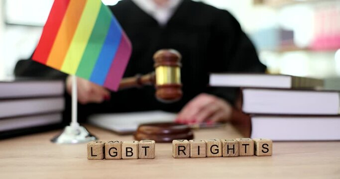 Lgbt rights word near rainbow flag and judge in courtroom closeup 4k movie slow motion. Legalization of samesex marriage concept