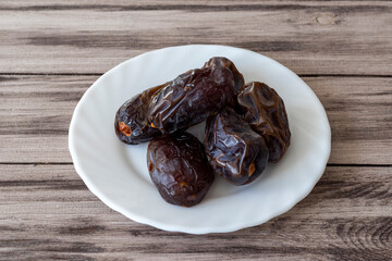 Large royal dates on a white plate on a wooden background