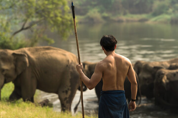 Back view shirtless mahout look after group of Asian elephants, Elephant Mahout