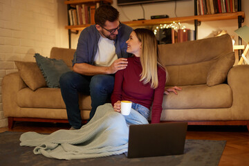 Obraz premium Young couple spending evening at home using laptop