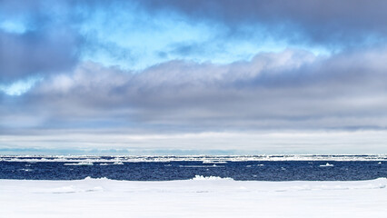 Naklejka na ściany i meble The Arctic sea near Svalbard, with many icebergs towards the horizon and a summer blue sky with clouds. Panoramic view of the polar ice cap.