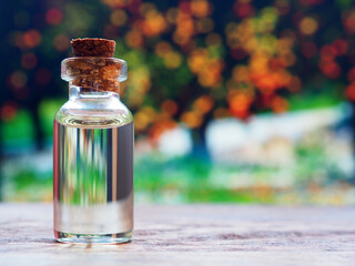 Glass bottle of orange essential oil on background of orange trees