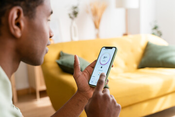 Crop black man using smartphone on sofa