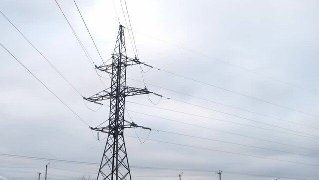 High voltage electric tower with wires on overcast sky background. Transmission power line. Parts of electrical equipment and high voltage power line insulators.