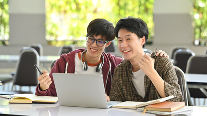 Two collage students looking at laptop, doing homework in campus. Youth lifestyle and education concept