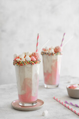 Strawberry Milkshake with marshmallows and raffaello and popcorn topping in transparent glass. Dessert food photography. 