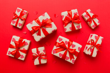Top view photo of valentine day decorations gift box with red ribbon bow on colored background. Holiday gift boxes with top view